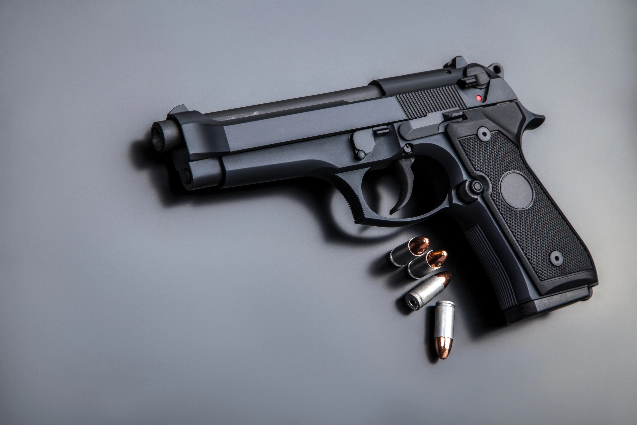 black pistol with four rounds of ammunition lying on a table black pistol with four rounds of ammunition lying on a table